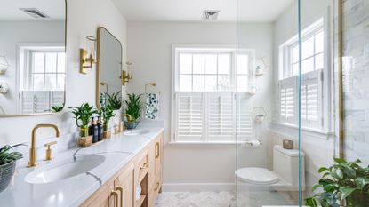 Learning how to maximize space in a small bathroom like this one is useful. It's a white bathroom with mirrors, a dual sink, shower, toilet, and window