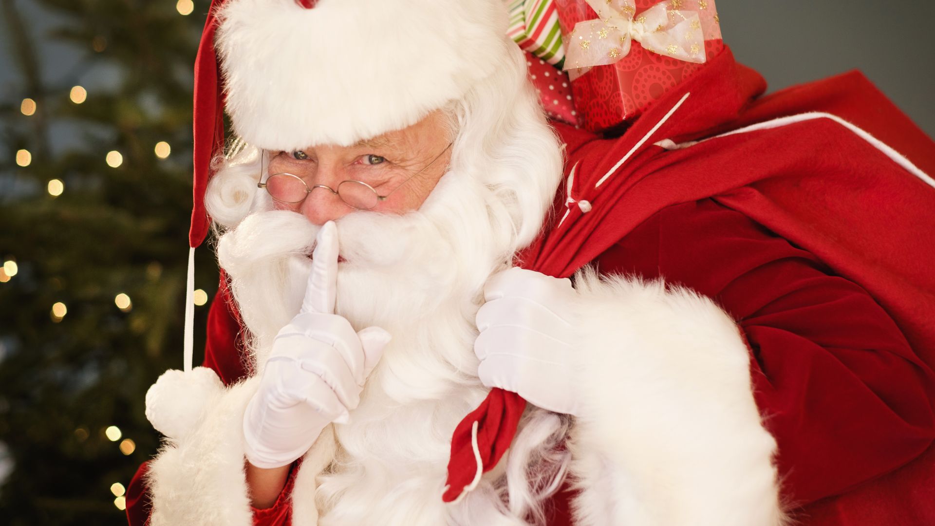 Father Christmas putting his finger to his lips with a sack of presents over his shoulder