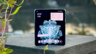 OnePlus Open står på en steinsøyle utendørs, med startskjermen aktiv.