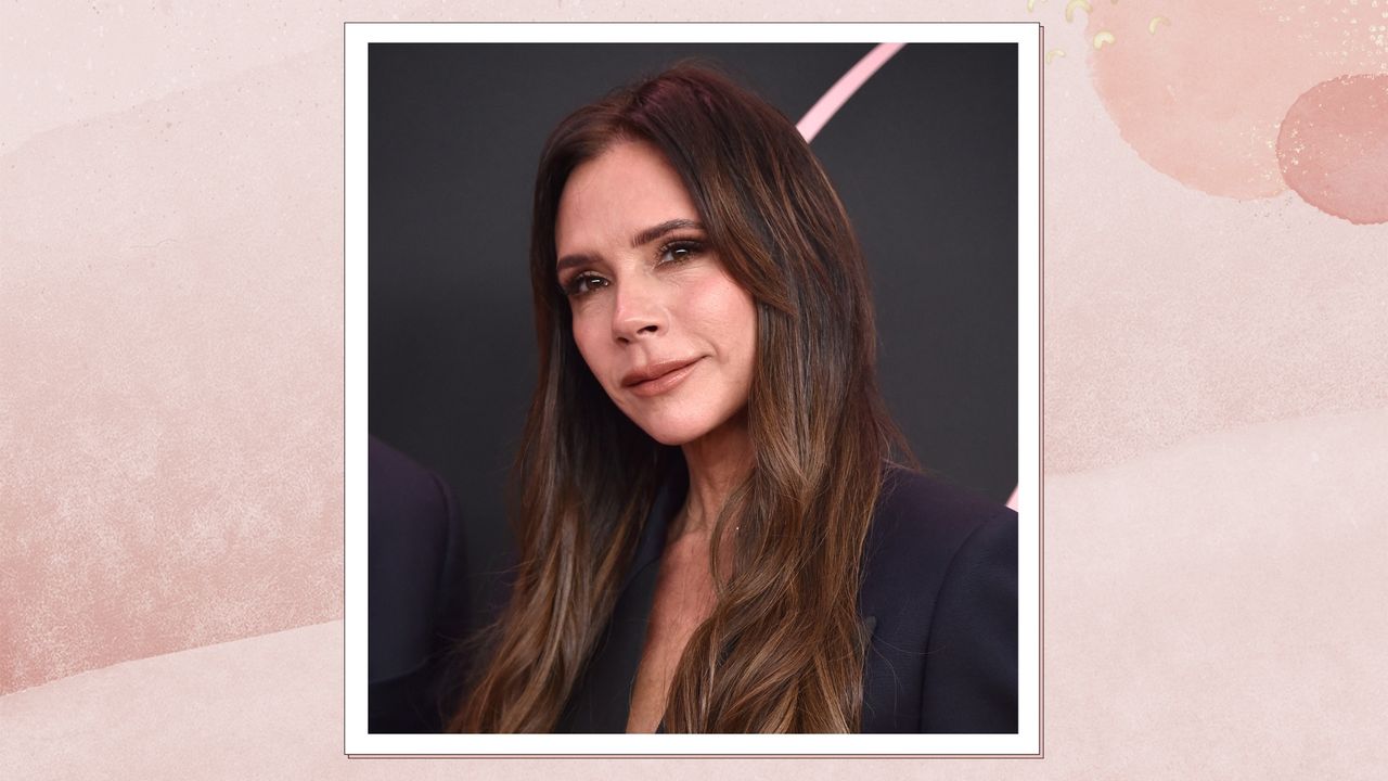 Portrait of Victoria Beckham smiling with curly brunette hair, on a pink watercolour background