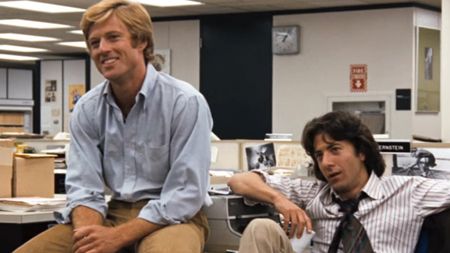 Robert Redford smiling, sitting next to Dustin Hoffman in All the President's Men