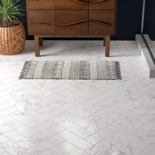 Gray herringbone tile floor in a bathroom with wooden sink vanity unit and potter spider plant in rattan basket