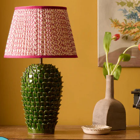 Pooky Stucco lamp with red lampshade and green bottom on a wooden table