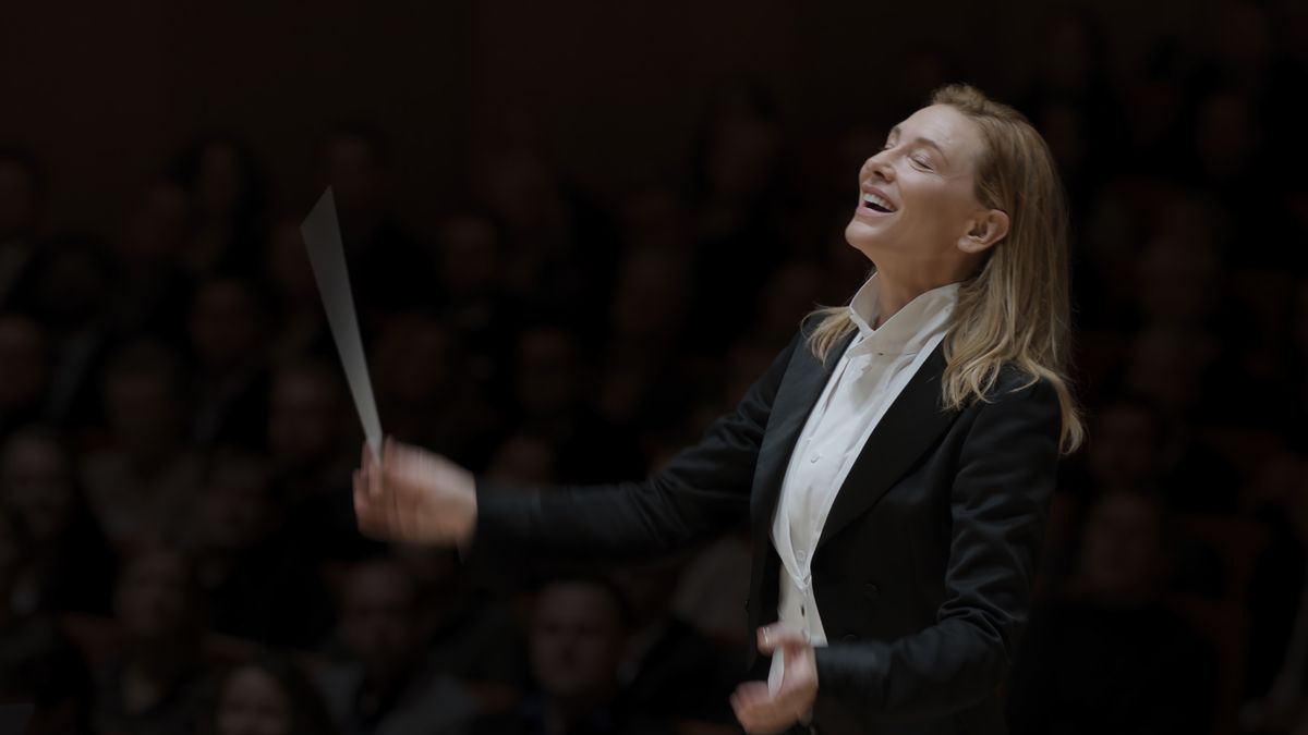 Cate Blanchett in Tar, wearing a suit and waving a conductor&#039;s baton