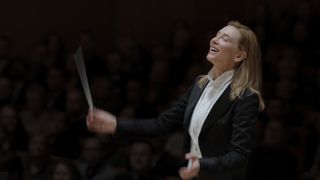 Cate Blanchett in Tar, wearing a suit and waving a conductor's baton