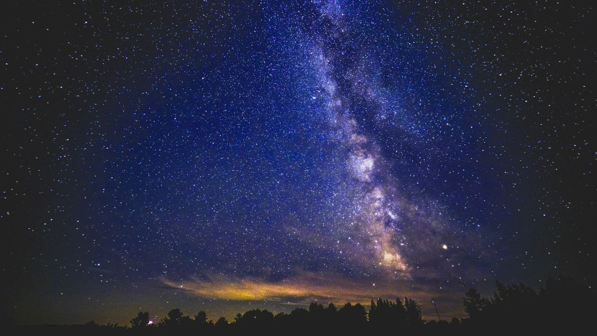 在夜空中可以看到銀河系的閃閃發光風格,森林中的深藍色和黃色。