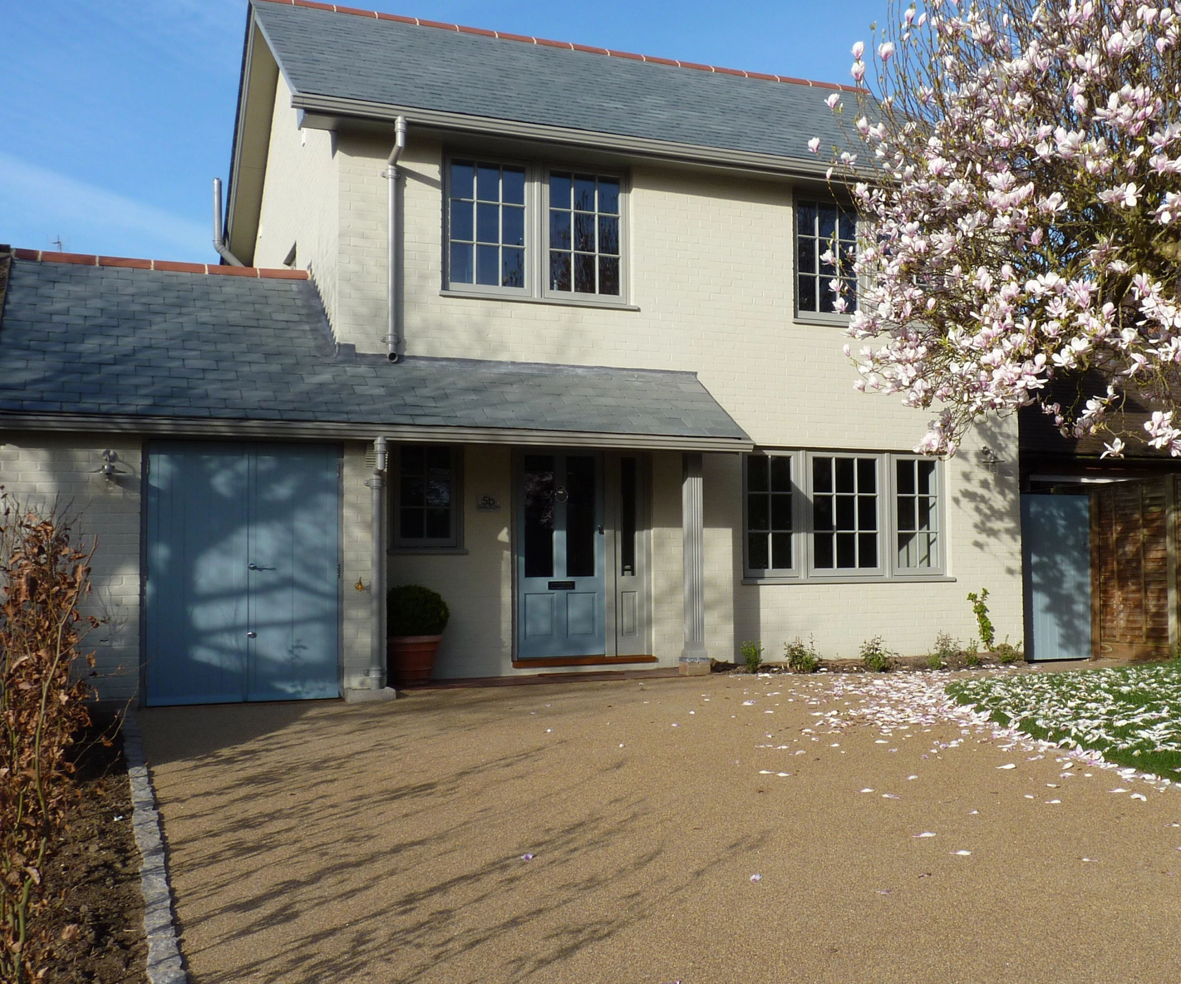 garage with pale blue doors matching colour of front door on cream rendered house