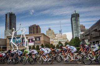 The peloton passes by the Denver skyline.