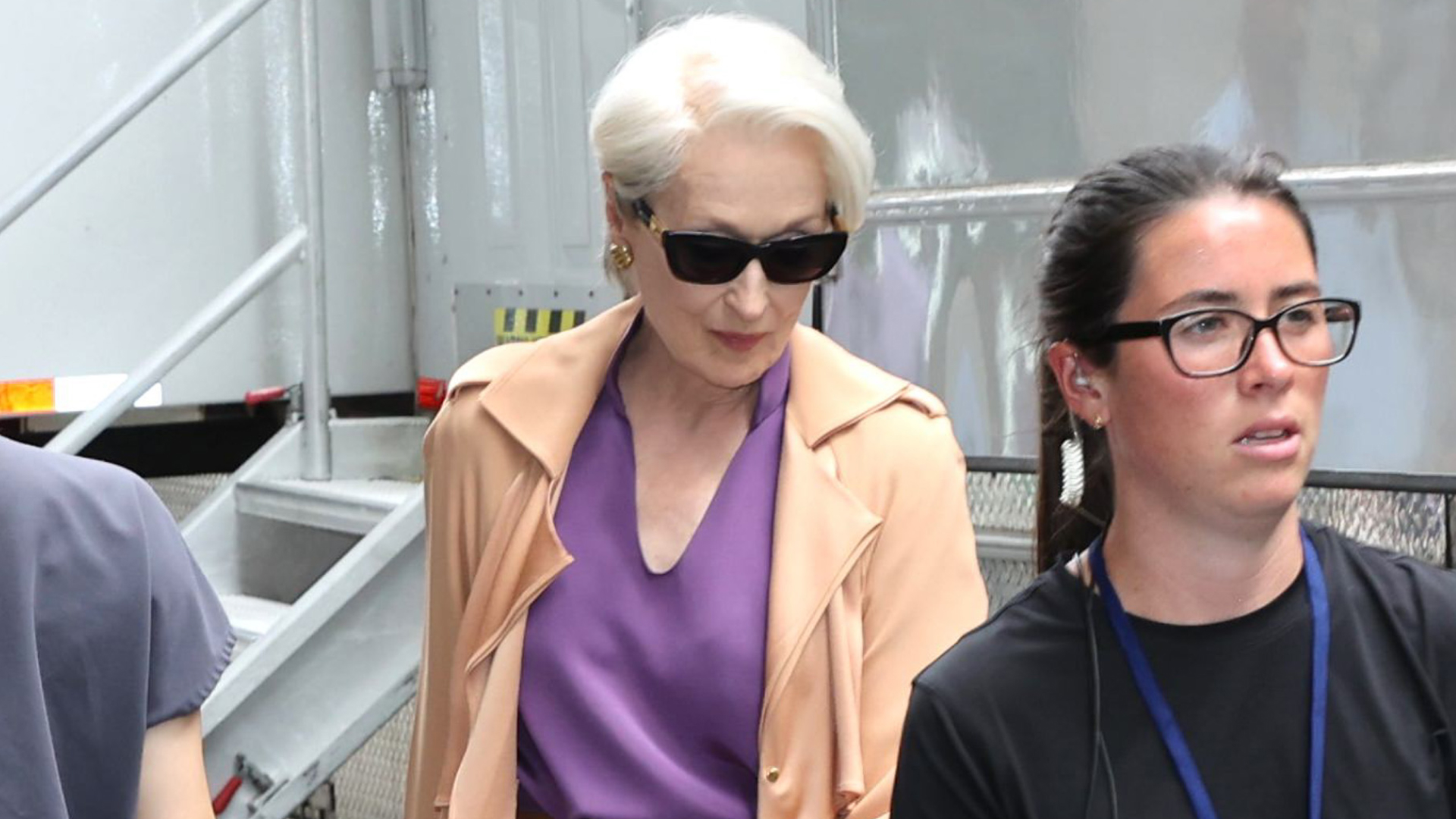 Meryl Streep in character as Miranda Priestly wearing a purple top and carrying a Collina Strada water bottle