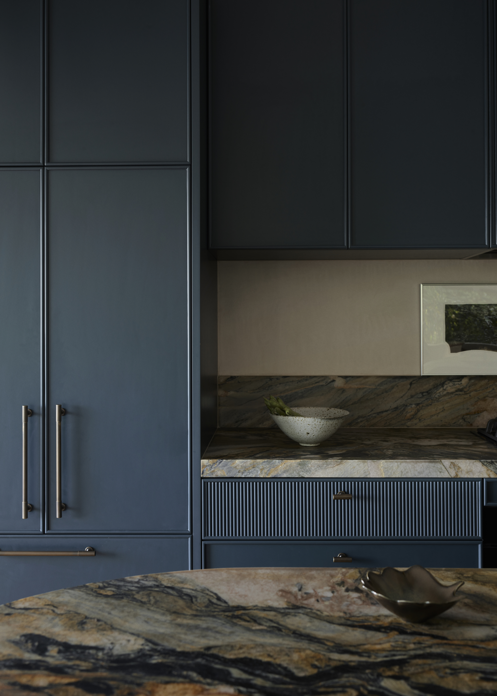 A navy blue kitchen with marble counters