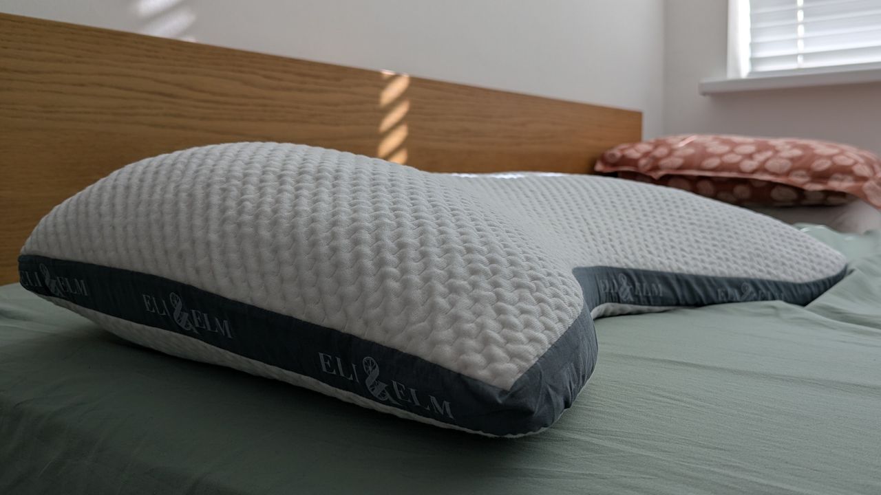 Eli and Elm Side Sleeper Pillow on the bed with a green bedsheet in a brightly lit room