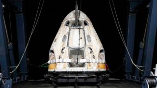 white space capsule rests on the deck of a recovery ship