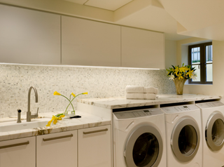 White laundry room with integrated washing units and tile backsplash