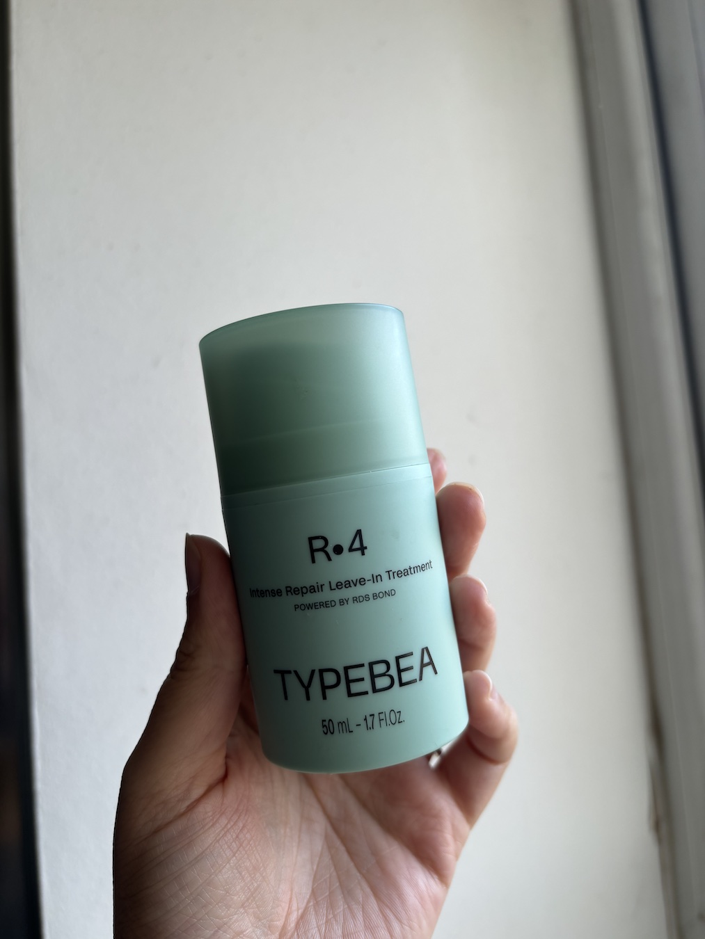 Mica Ricketts holding TypeBea R4 Intense Repair Leave-In Treatment