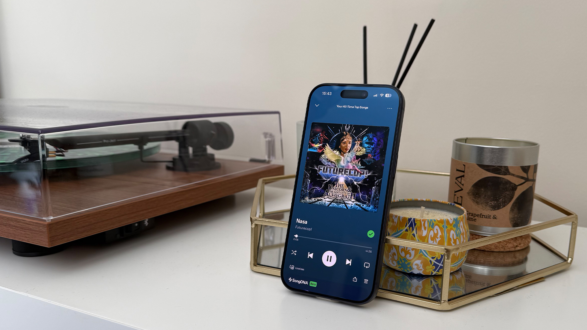 Apple iPhone 17 Pro smartphone leaning upright next to record player, on screen is Spotify player