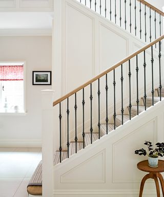 neutral hall with wood and metal banister and striped stair runner