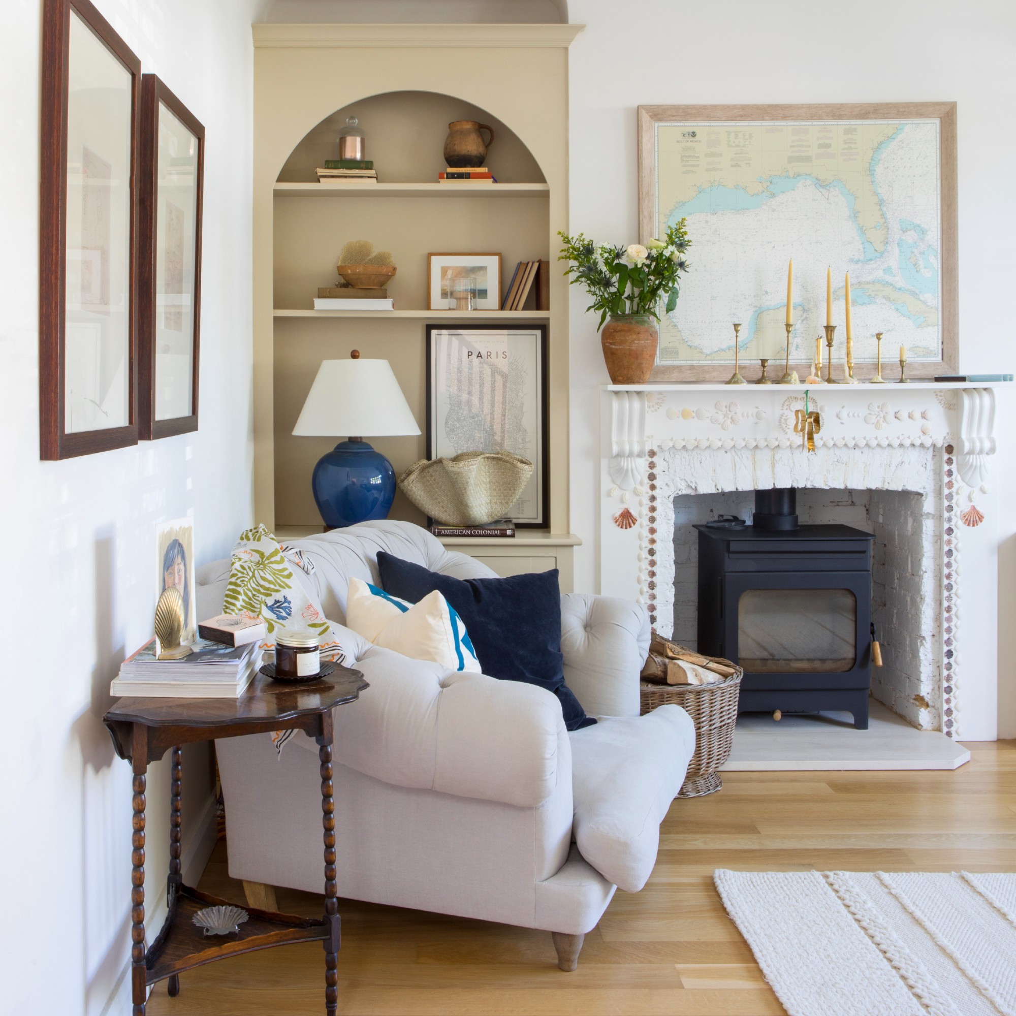 A living room with a fireplace, a contrasting bookcase built into an alcove and a neutral sofa positioned a few inches away from the wall