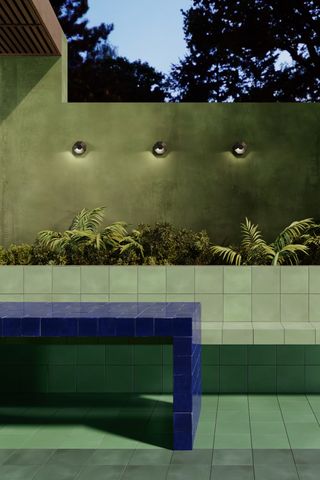 Green tiled patio with built-in seat and green wall with lights