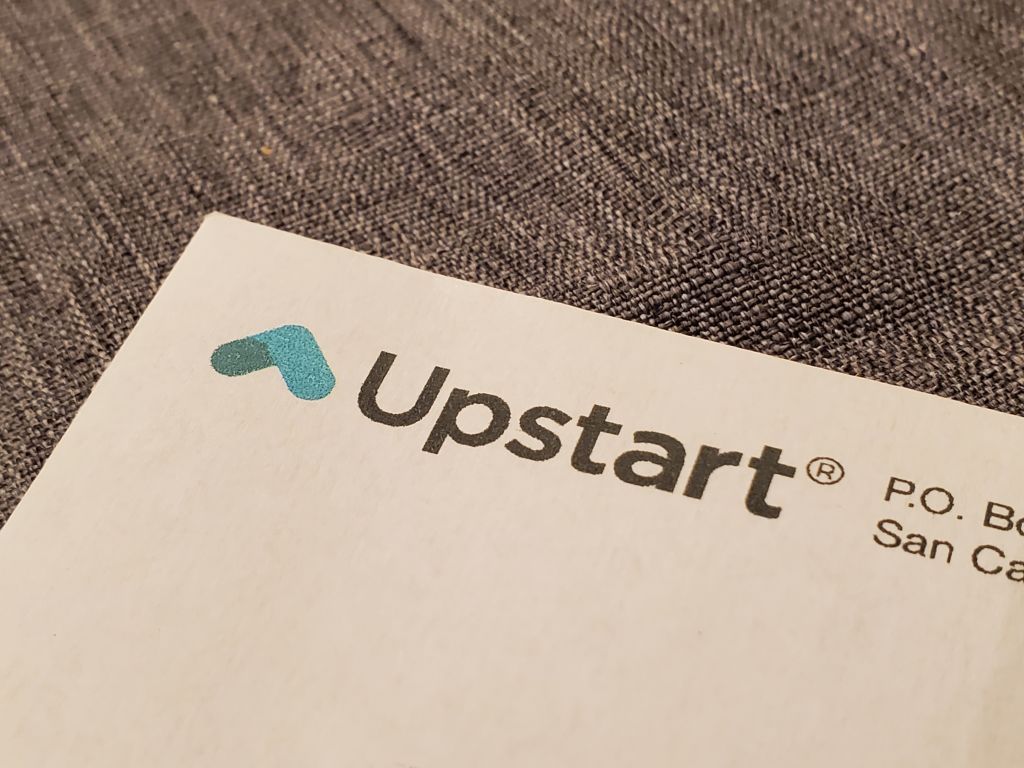 Logo for Upstart AI lending platform on a piece of paper that&#039;s placed on a gray cloth surface