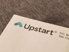 Logo for Upstart AI lending platform on a piece of paper that's placed on a gray cloth surface