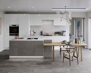 a modern industrial style kitchen with gloss white cabinets, concrete style island cabinets, inbuilt appliances, split level island with table