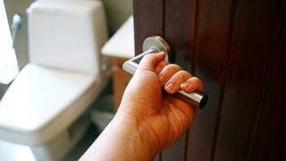 Person holding handle on bathroom door