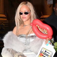 Rihanna wearing a silver bustier and gray fur vest.