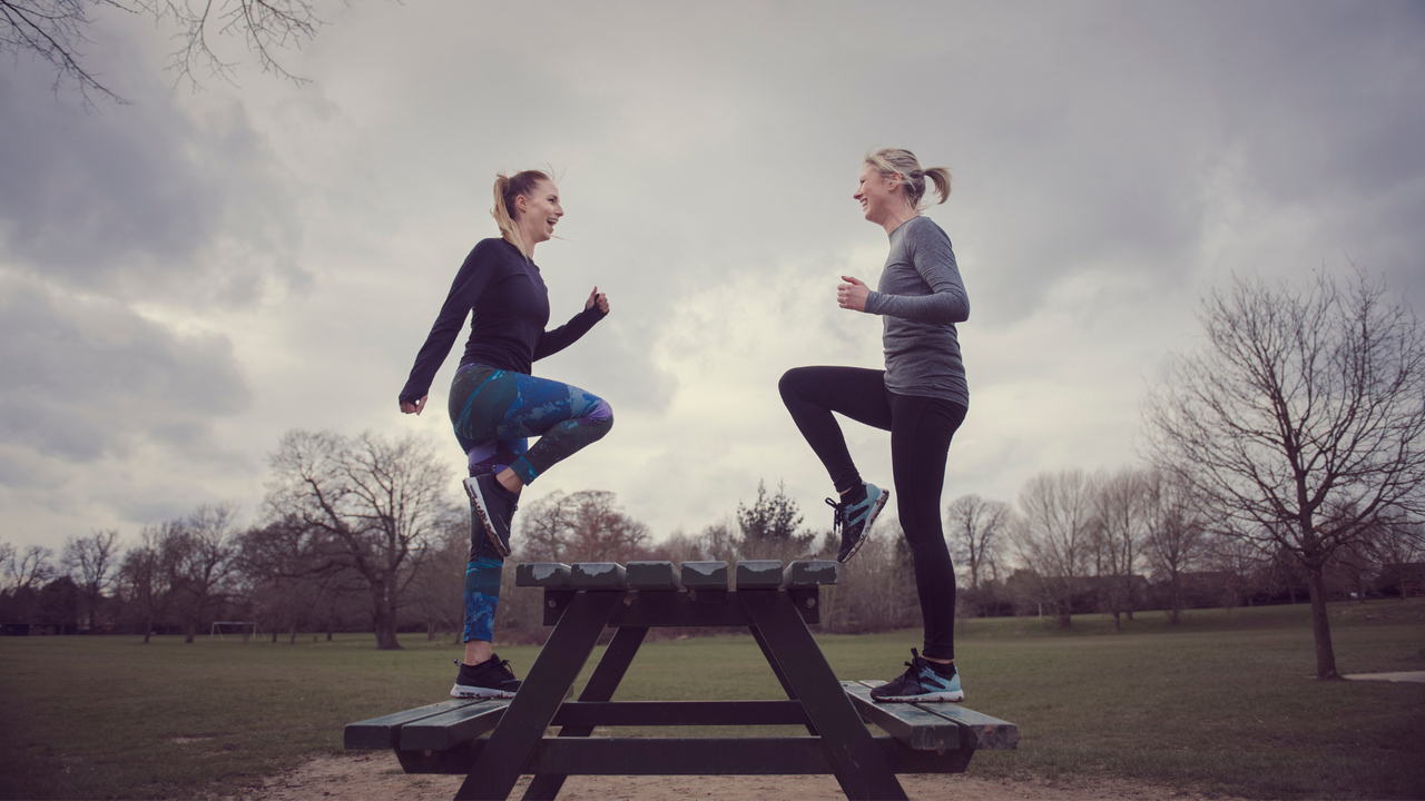 Two ladies doing step ups on park bench