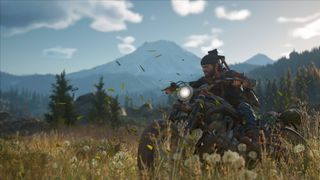A screenshot from Days Gone showing protagonist Deacon riding through a field on his motorcycle.