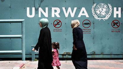 Women walk in front of the HQ of the United Nations Relief and Works Agency for Palestine Refugees