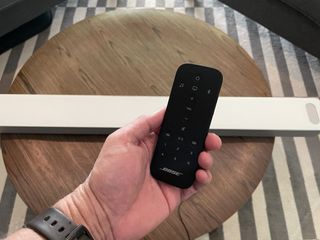 A hand holding the remote control to Bose Smart Soundbar 900