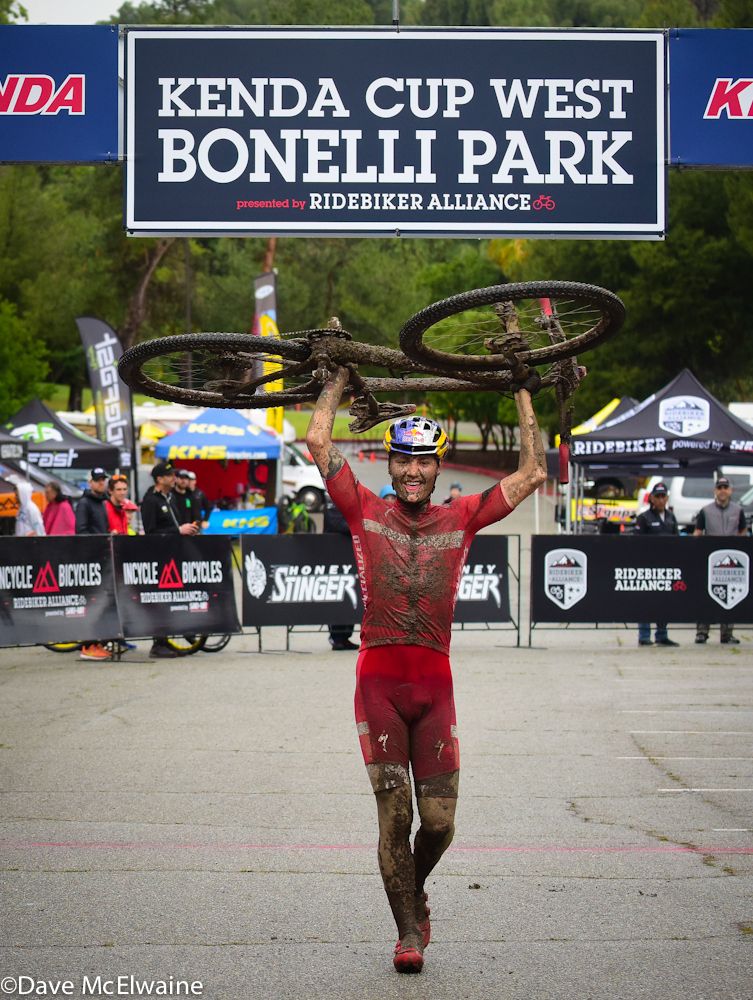 Simon Andreassen (Specialized) carries his Specialized bike over the finish line.