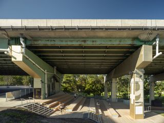 The underside of a bridge with benches and a staircase below it.