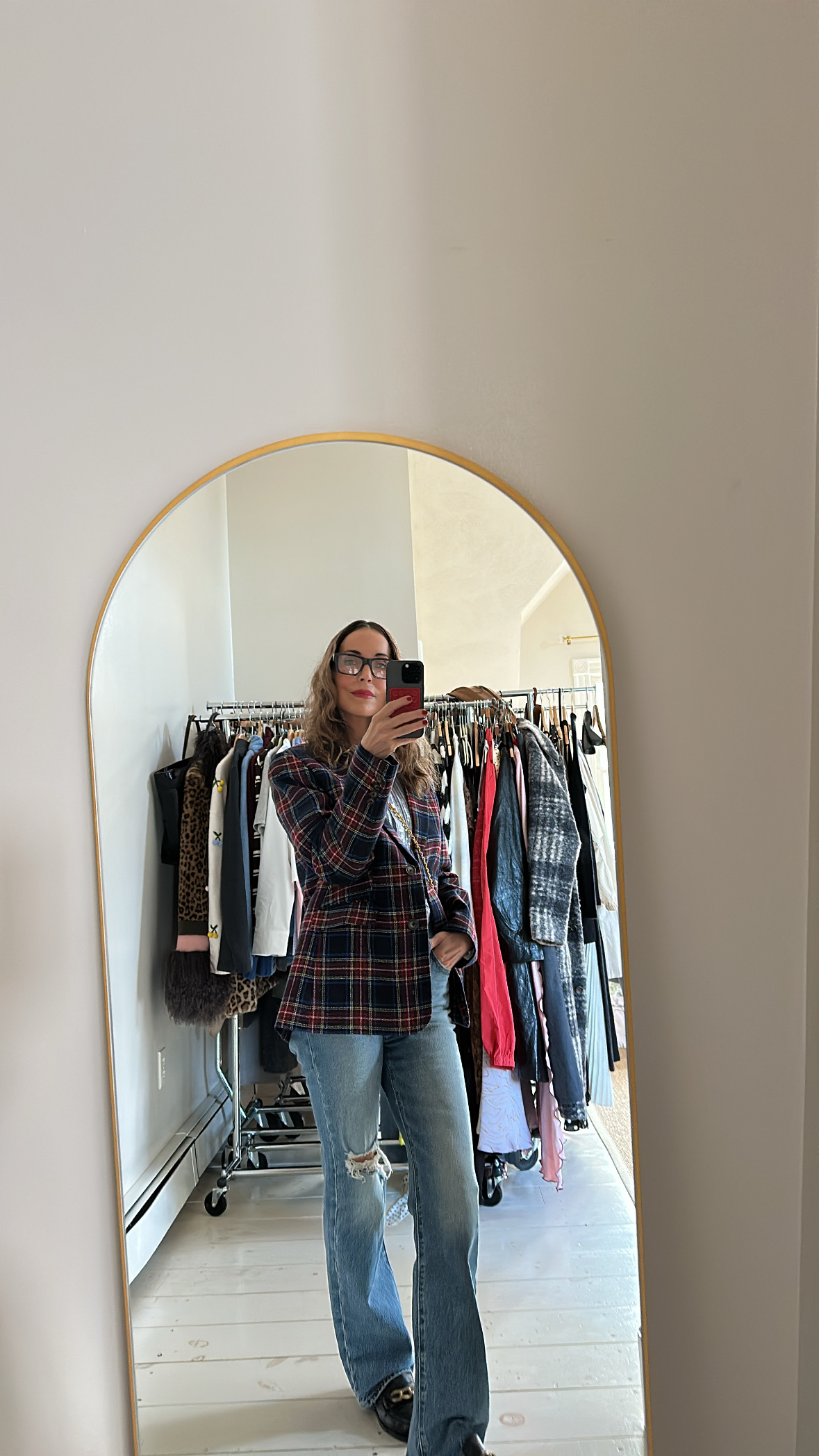 Larissa Mills wearing blue jeans, a white tee, and a red plaid blazer