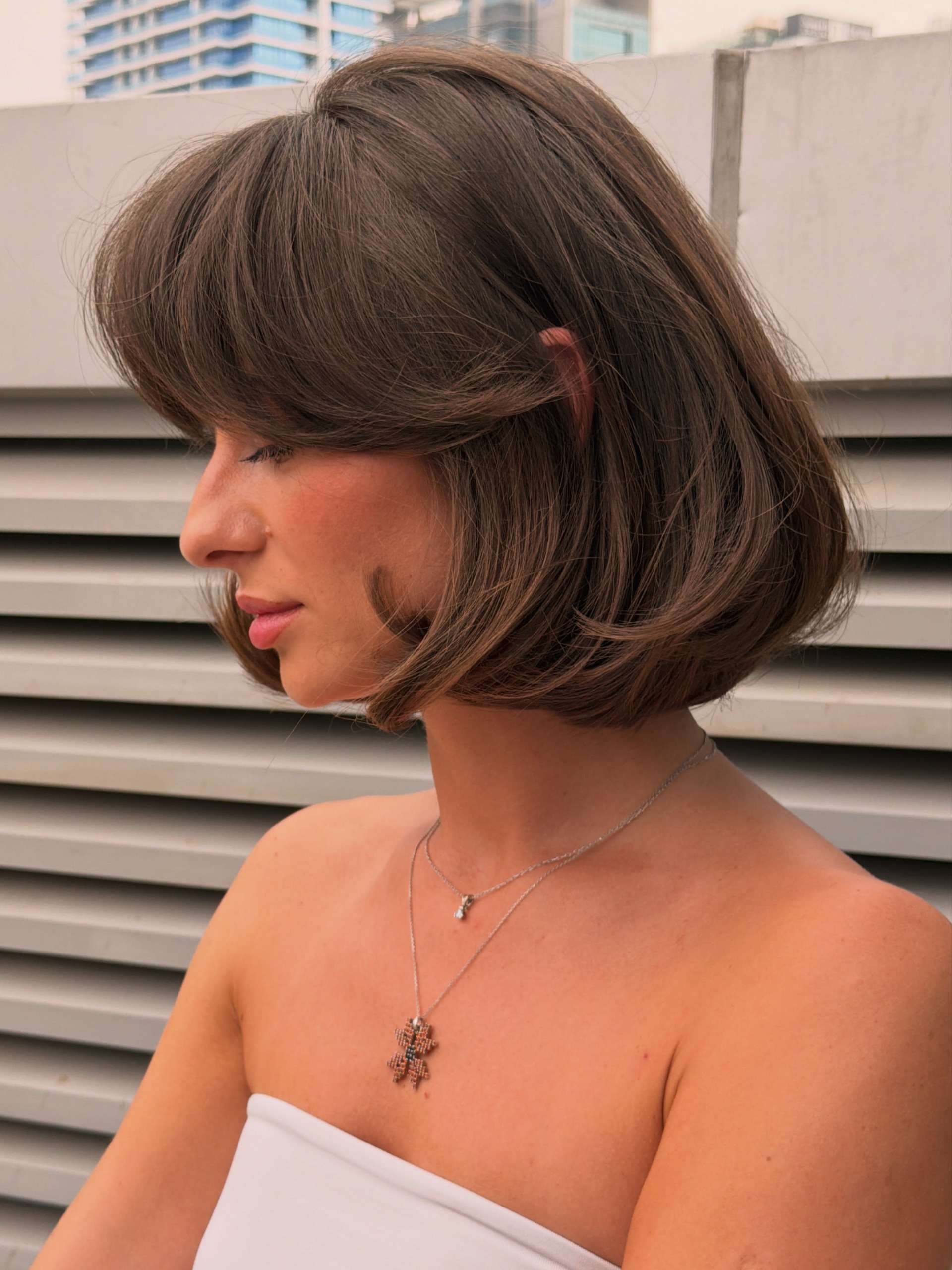 curtain fringe french bob person looking to the side with white tube top on