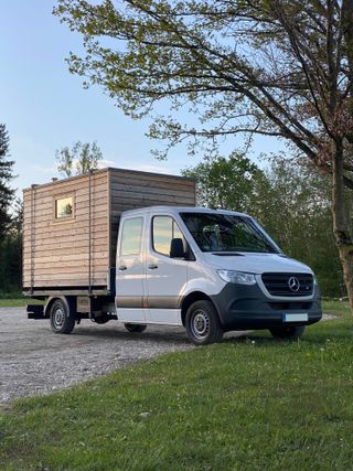 Wooden cabin structure loaded on back of a white van