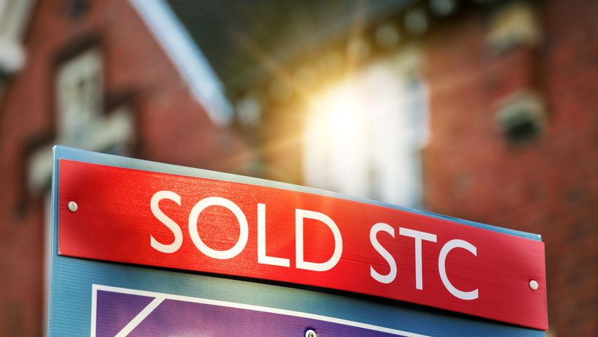 Sold sign in front of house with sun shining on window