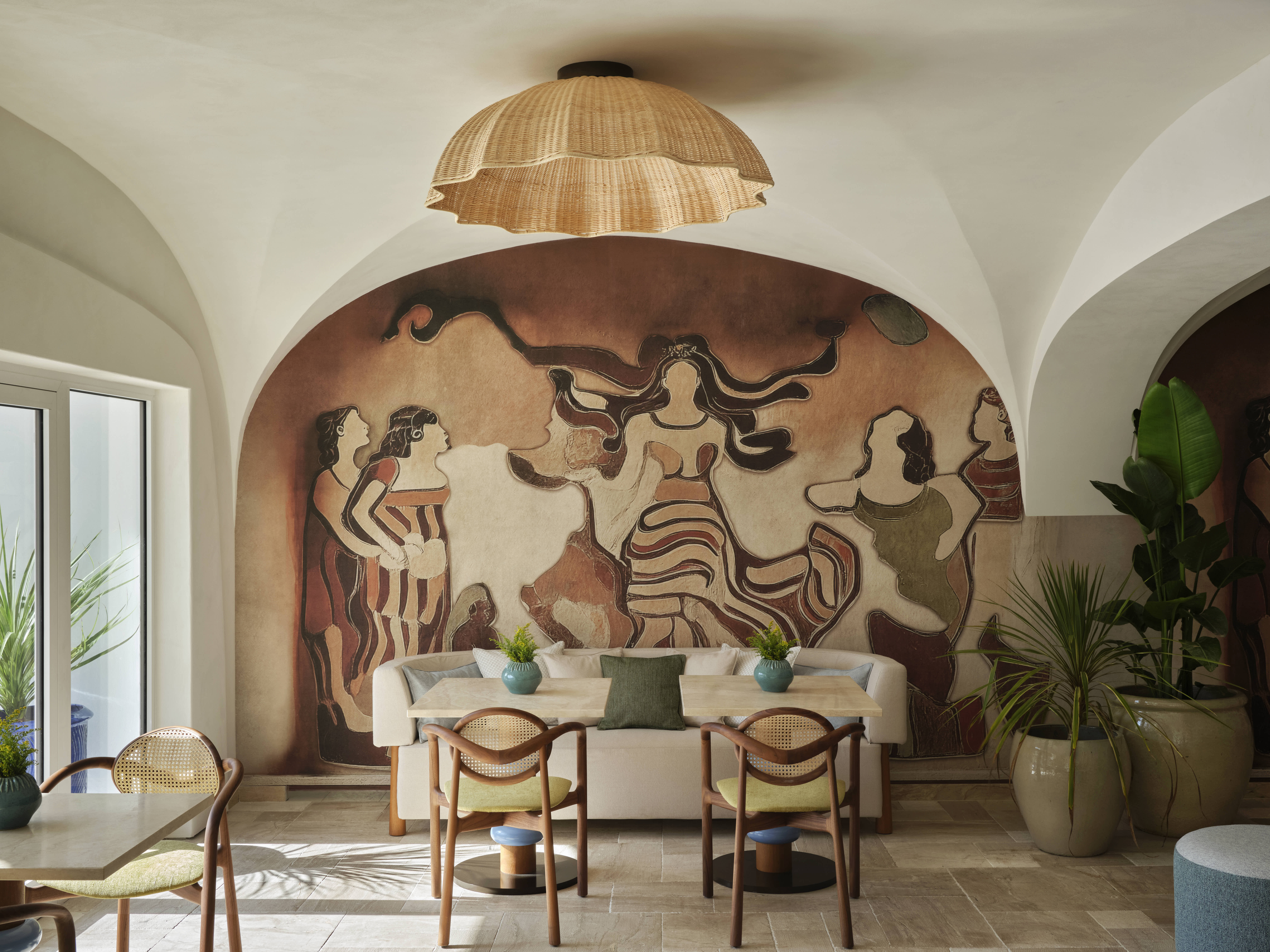 A sea-facing resort with wood and stone-encrusted pieces, warm quirky lighting throughout, eye-catching textiles, and a whitewashed palette catches stunning views of the outside from its terrace.