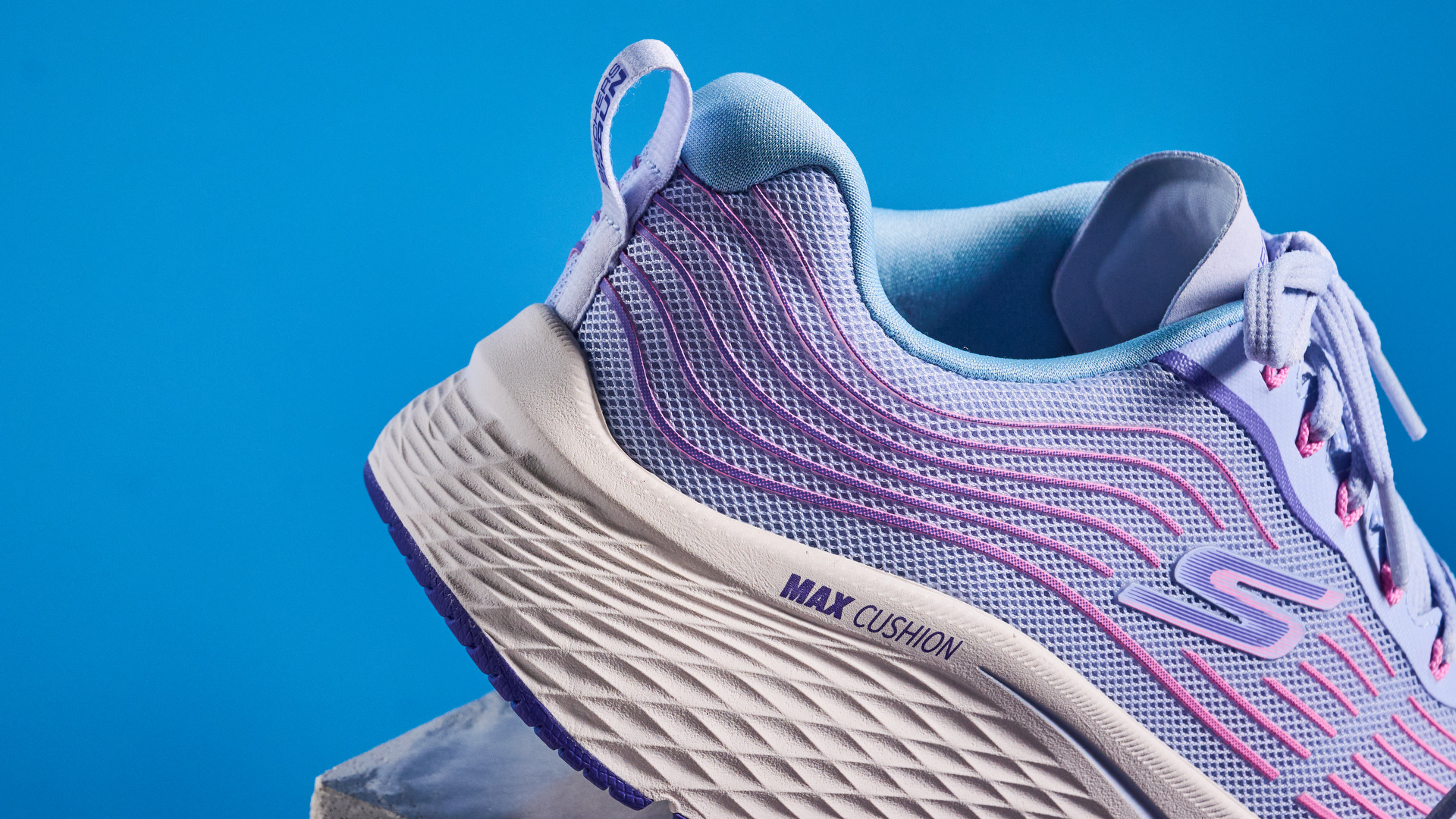 Skechers Max Cushioning Elite 2.0 running shoes photographed in front of a blue background.