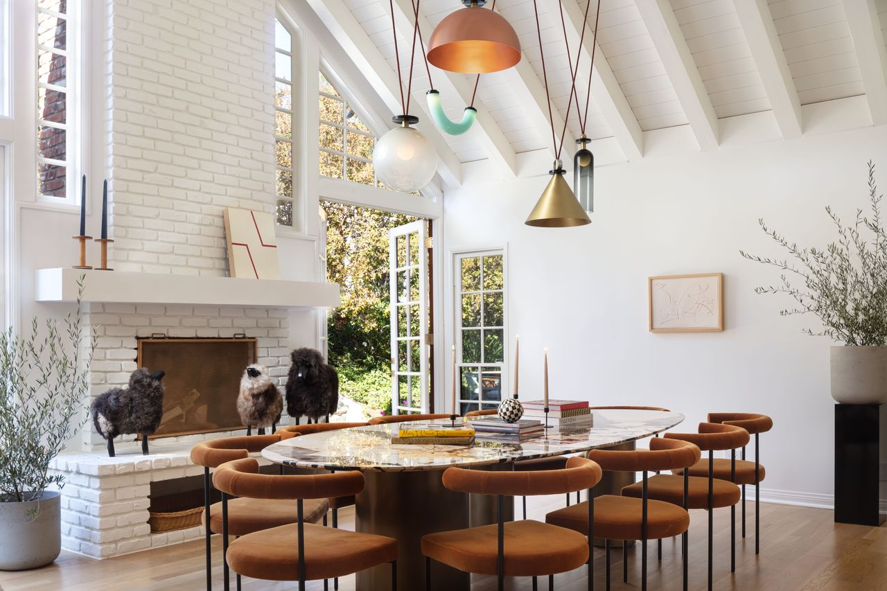 oval dining room table with blue and metallic pendant lights and rust colored chairs