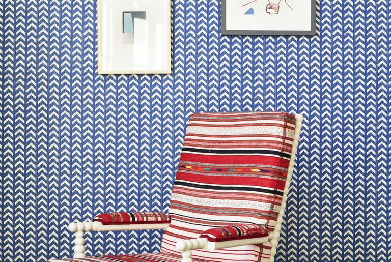 blue and white wallpaper with a red ikat chair