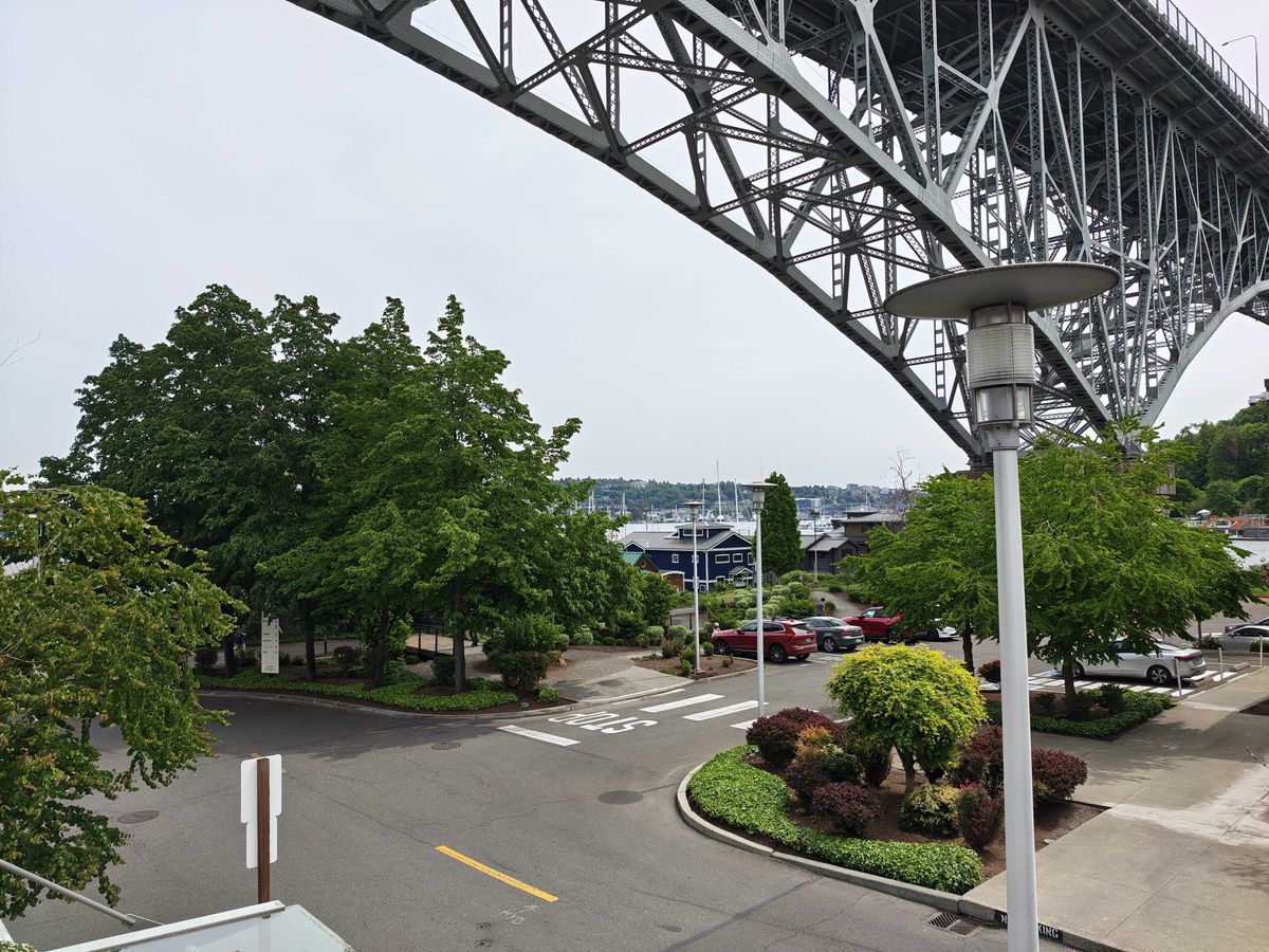 A church in the distance with trees all around and a bridge above