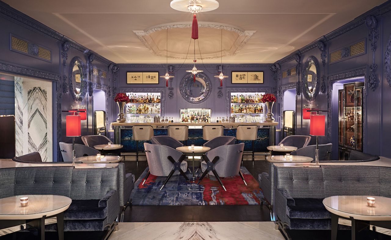 A bar in blue tones with red lampshades and silver highlights