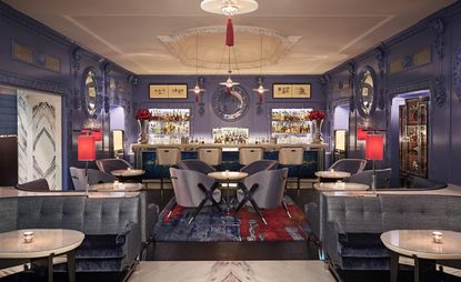 A bar in blue tones with red lampshades and silver highlights