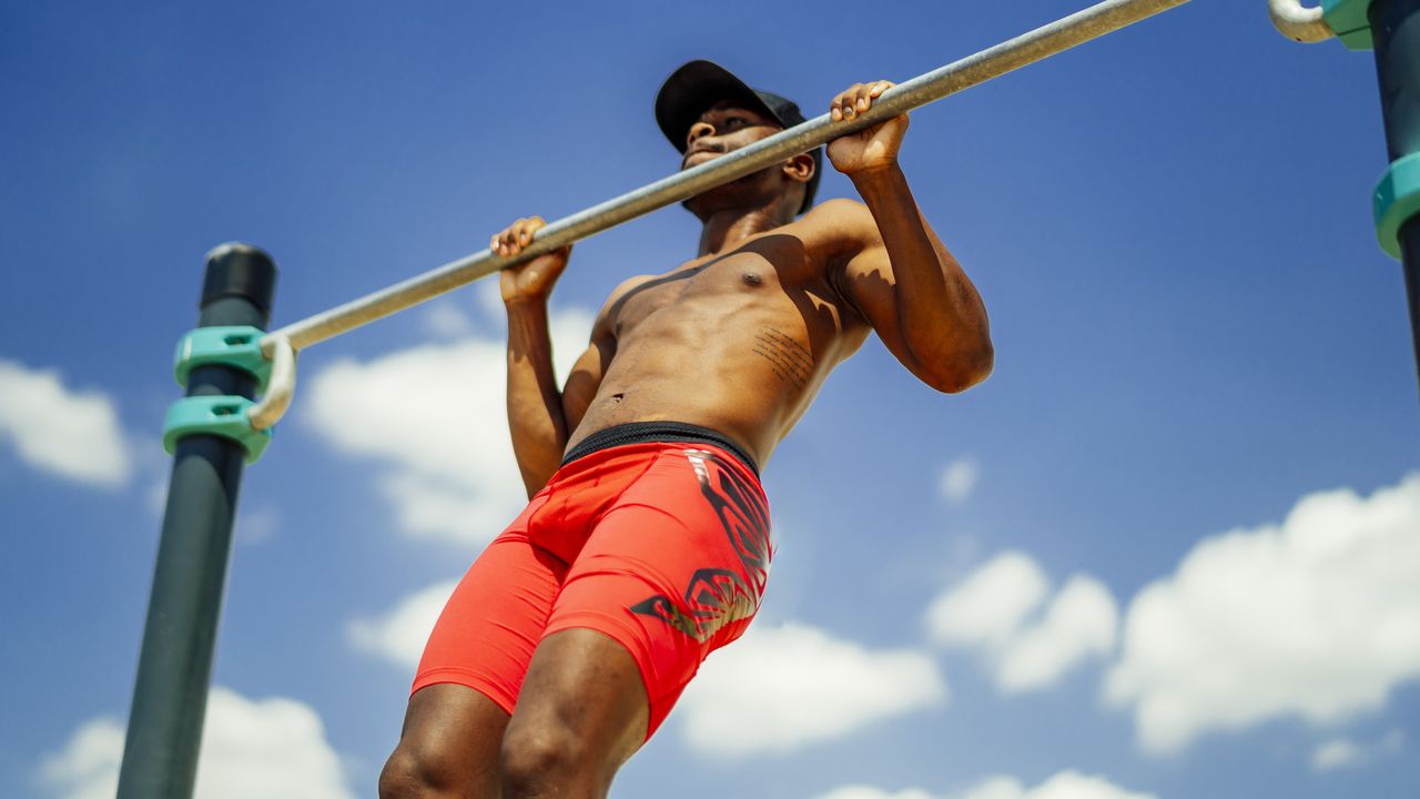 100 pull-ups a day challenge: pictured here, a young athletic-looking person goinf pul--ups outdoors