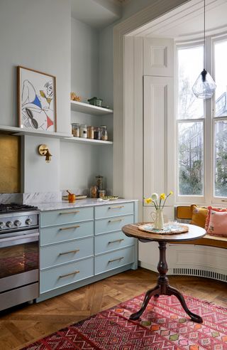 Pastel blue kitchen with colorful rug and cushions