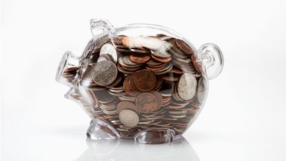 A clear piggy bank is filled with coins.