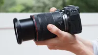 A side-on shot of a pair of hands holding the Canon EOS RP, with the lens pointing to the left 