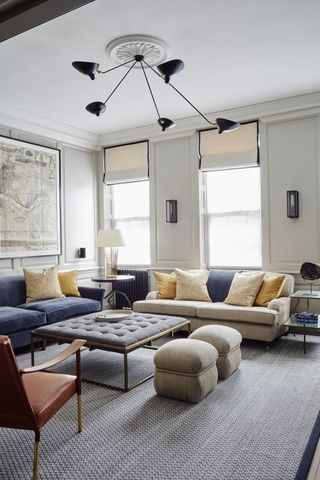 Living room with pale gray walls, coving, cream and blue sofas and gray rug