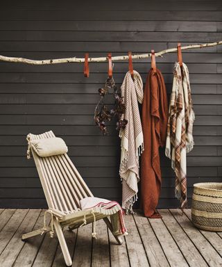 Small garden decking ideas in rustic exposed wood with wooden chair and terracotta throws.